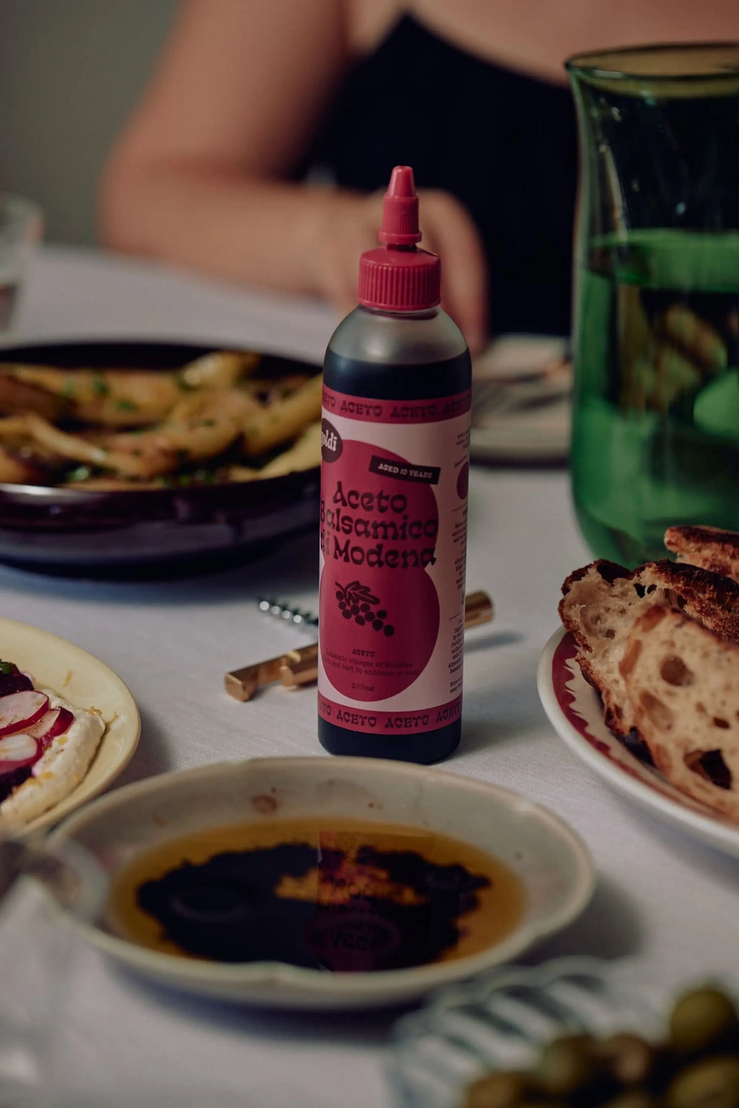 Balsamic vinegar in squeeze bottle on a dining table with food.