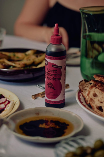 Balsamic vinegar in squeeze bottle on a dining table with food.